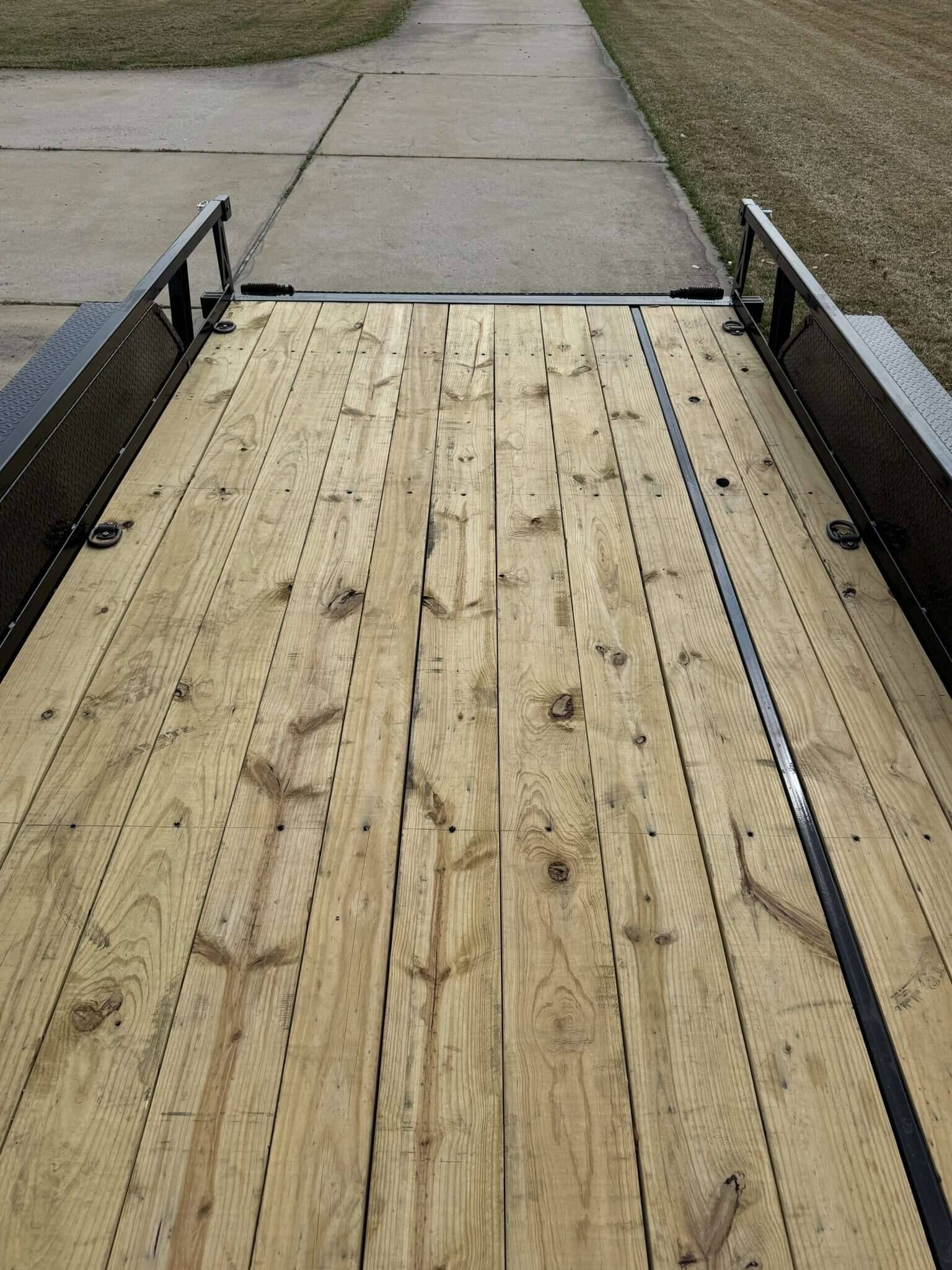 Trailer with wooden deck and side rails for transporting large items securely.