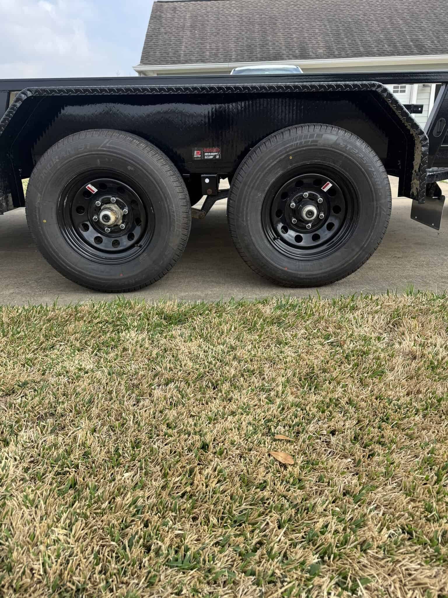 Durable black utility trailer with dual axles, ideal for hauling equipment and materials.